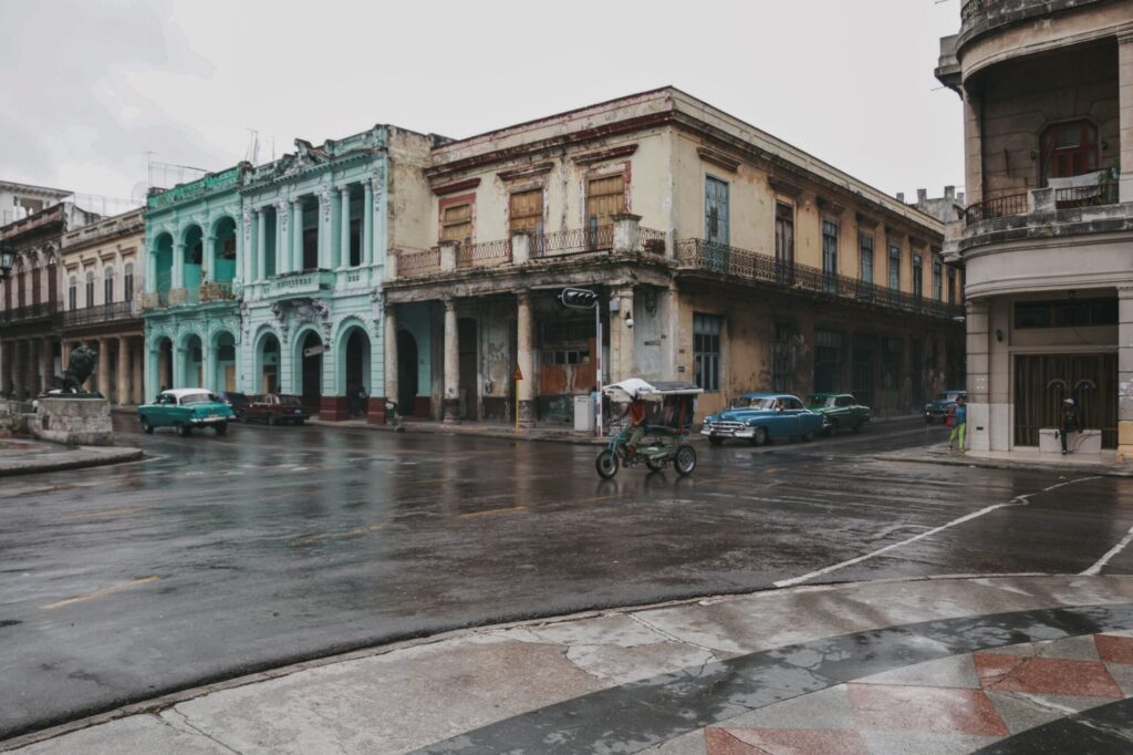 A vintage street scene with classic cars and old buildings in Havana, Cuba after rain.