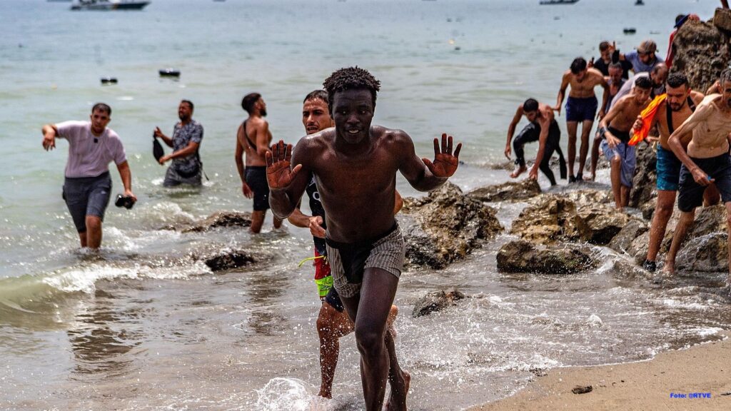 Personas llegando a una playa rocosa desde el mar.