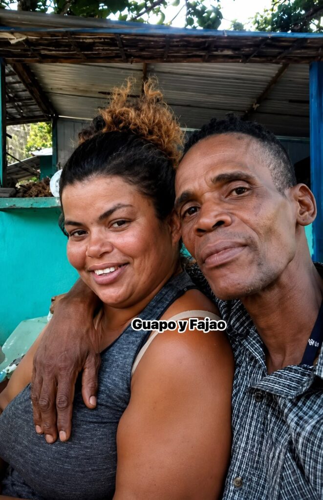 Pareja sonriente abrazada bajo una estructura rústica al aire libre.