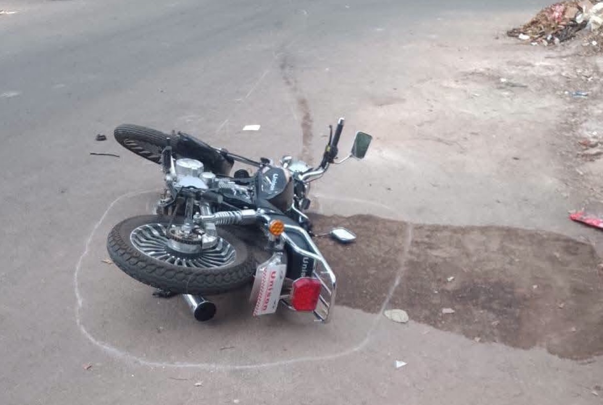 Moto negra accidentada en la carretera marcada con tiza blanca.