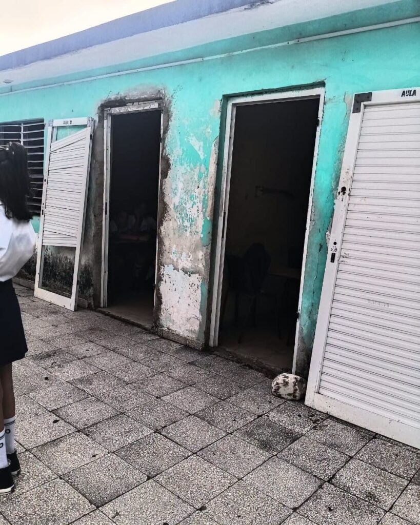 Fachada deteriorada de una escuela con aulas abiertas.