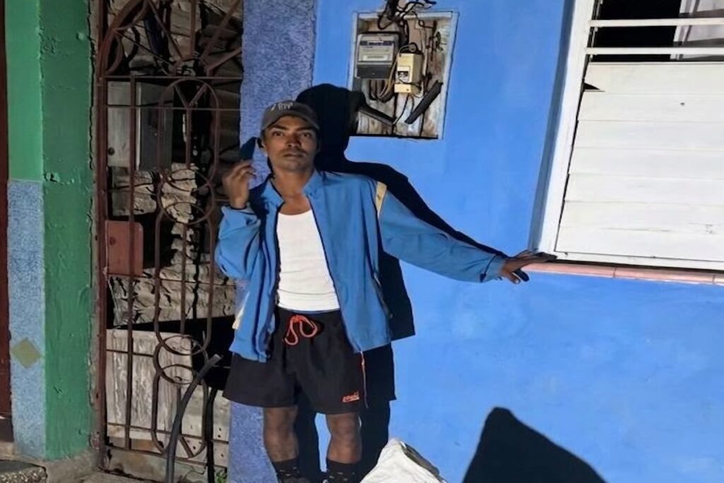 Hombre posando frente a una pared de color azul brillante.