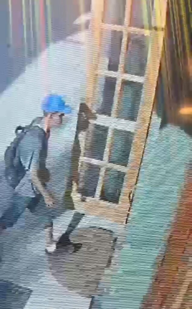 Persona con gorra azul caminando frente a una cristalera.