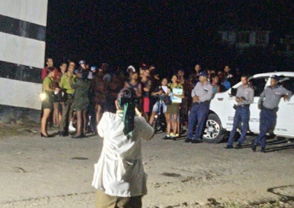 Oficiales y civiles reunidos de noche junto a una camioneta.