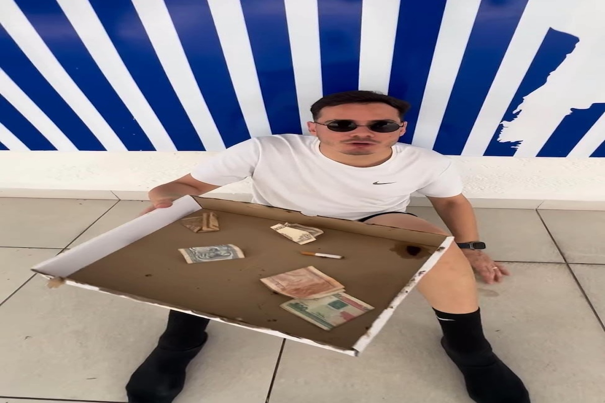 Hombre sentado en el suelo con billetes en una caja.