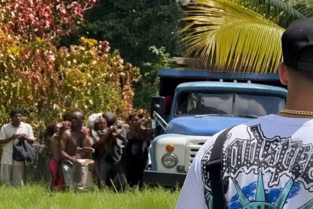 Hombre de espaldas frente a grupo de personas y camión.