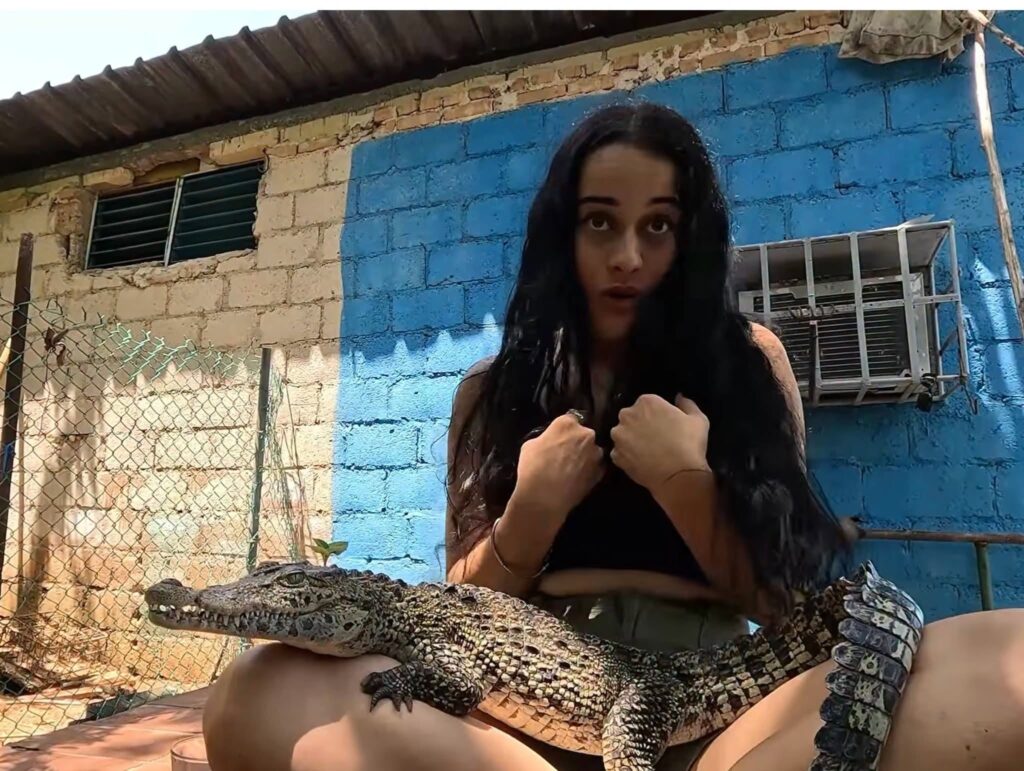 Mujer sentada con un pequeño cocodrilo sobre su regazo.
