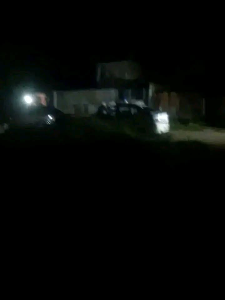 Vehículo con faros encendidos frente a una casa de noche.