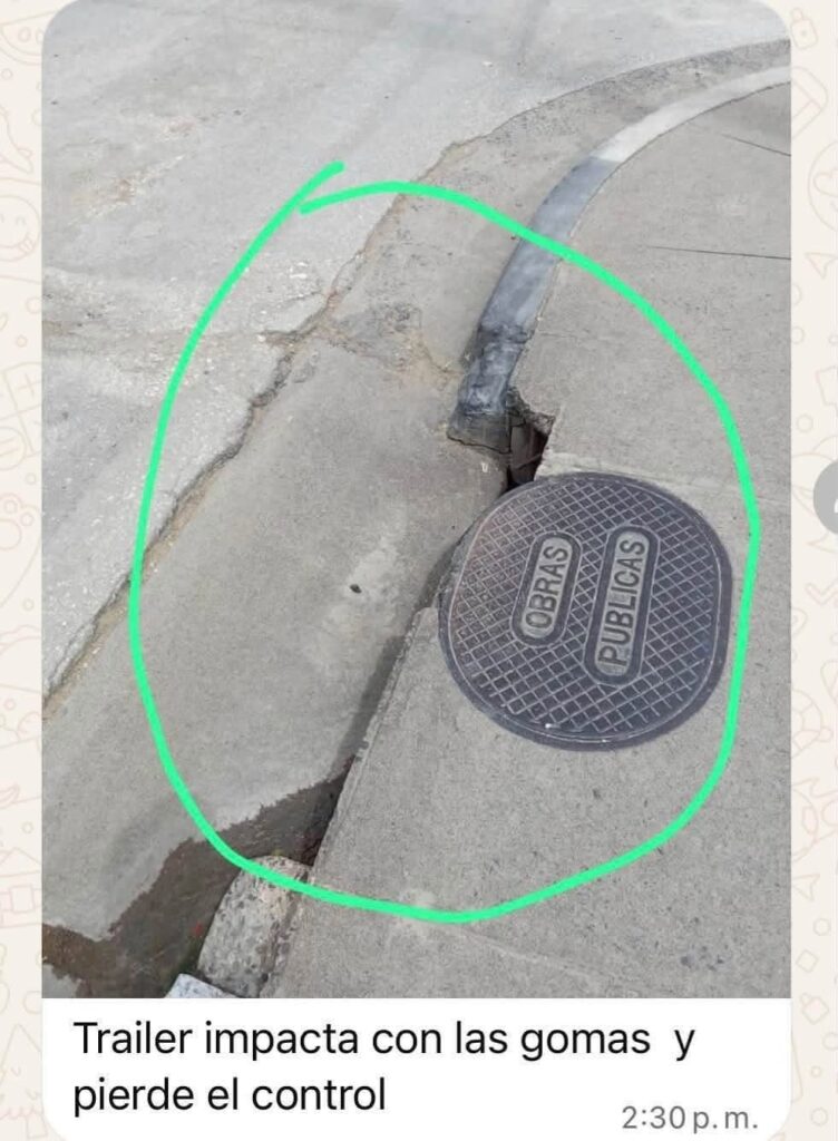 Grieta profunda en el asfalto junto a una alcantarilla.