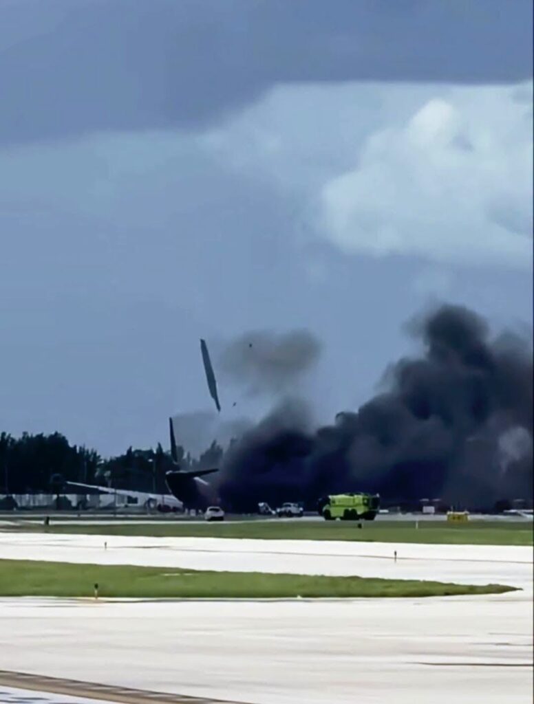 Avión accidentado en pista con humo negro y escombros.