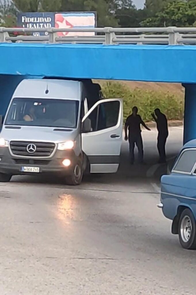 Furgoneta Mercedes-Benz atascada bajo un puente azul en Cuba.