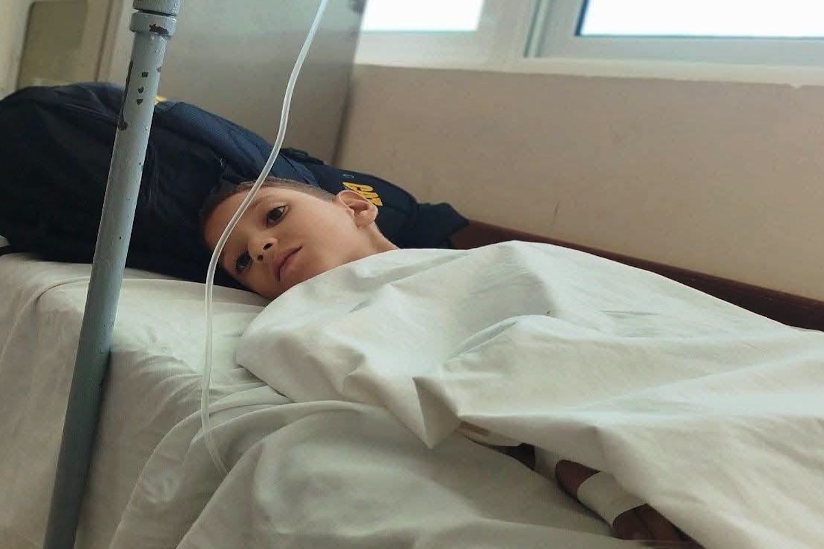 Niño pequeño en camilla de hospital con goteo intravenoso.