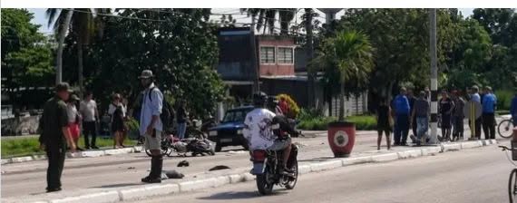 Personas y autoridades en una calle junto a una moto accidentada.