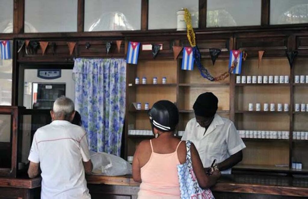 Personas en una farmacia cubana con estanterías de madera.