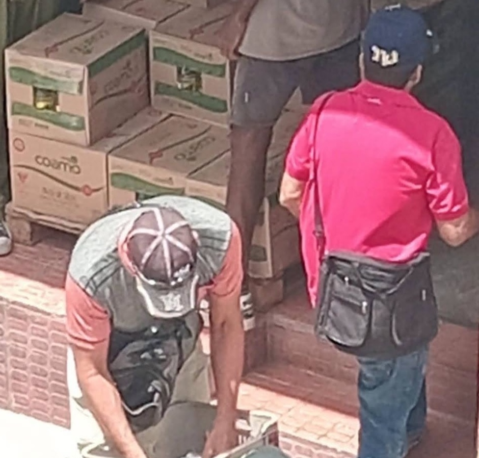 Hombres trabajando junto a pilas de cajas de cartón.