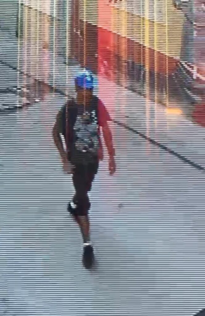Persona caminando con gorra azul en imagen con interferencia digital.