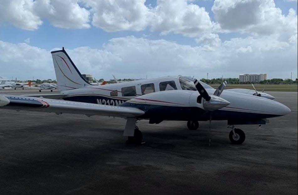 Avioneta bimotor blanca y azul estacionada en un aeropuerto.