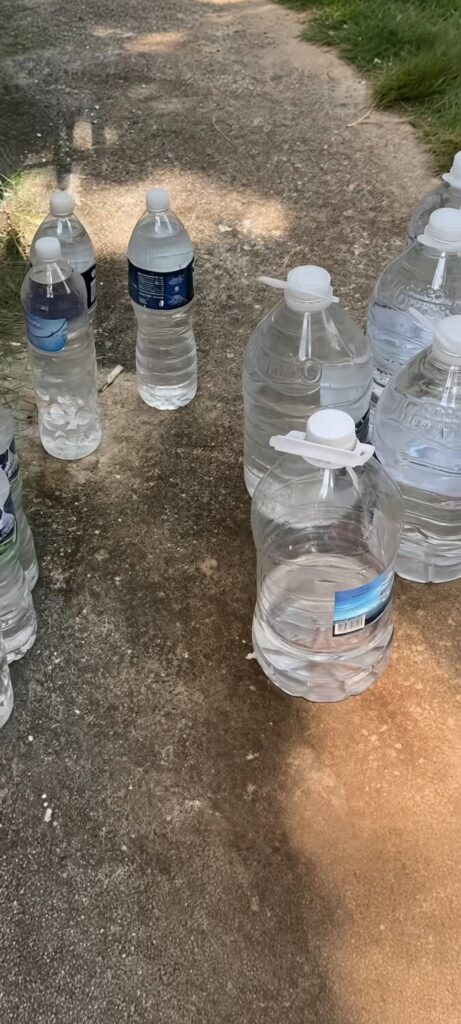 Varias botellas y garrafas de agua sobre suelo de hormigón.
