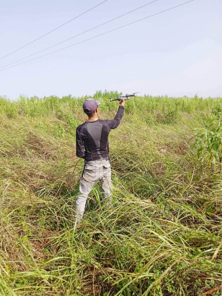 Hombre sosteniendo un dron en un campo de hierba alta.