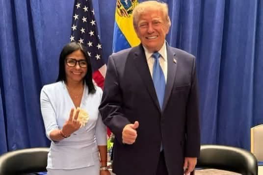Donald Trump y una mujer posando ante banderas nacionales.