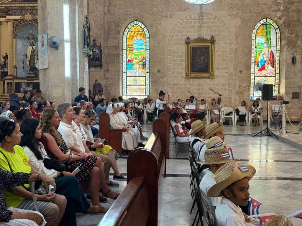 Fieles y niños con banderas cubanas en una catedral.