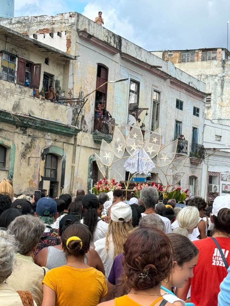 Procesión religiosa con trono de la Virgen ante edificios antiguos.