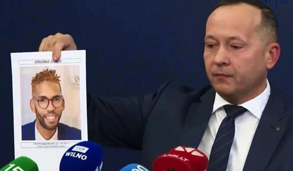 Hombre en traje sostiene cartel de una persona buscada.