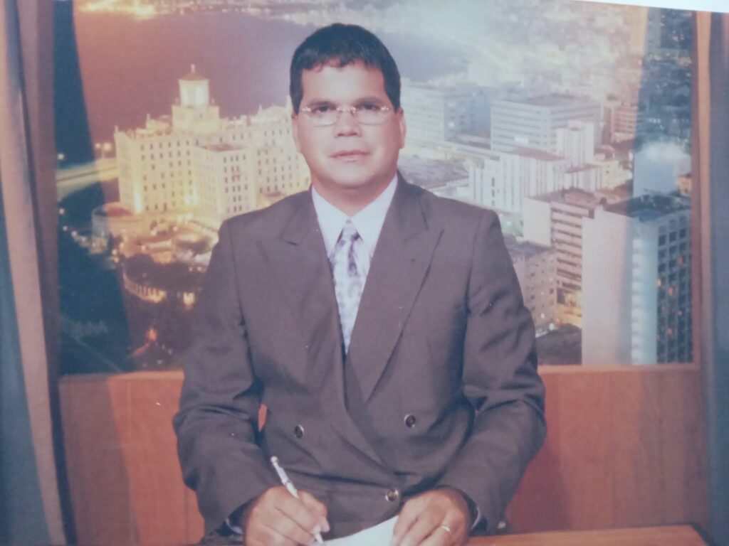 Hombre con traje en escritorio frente a ciudad nocturna.
