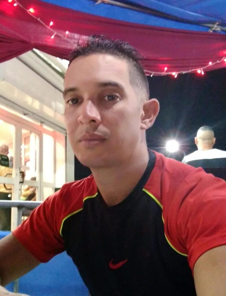 Hombre con camiseta deportiva roja y negra bajo luces nocturnas.