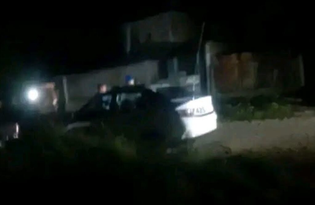 Coche blanco estacionado en una zona oscura de noche.