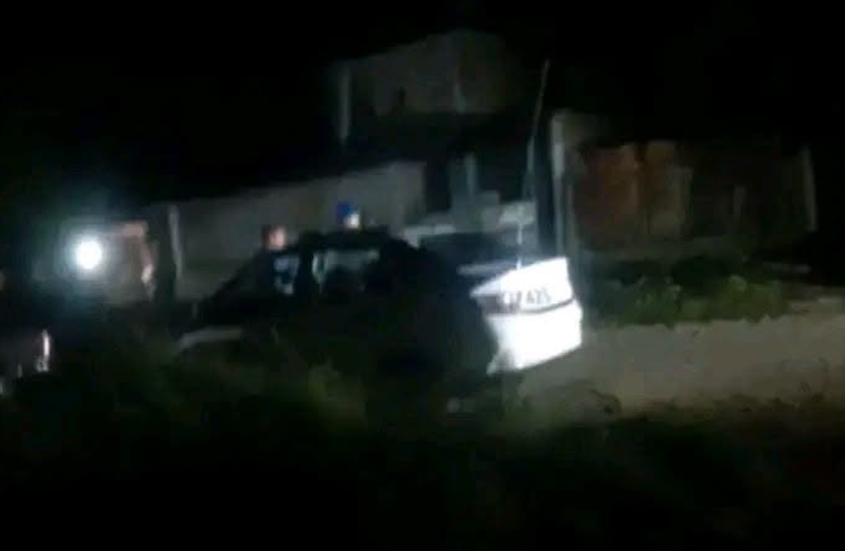 Coche blanco estacionado en una zona oscura de noche.