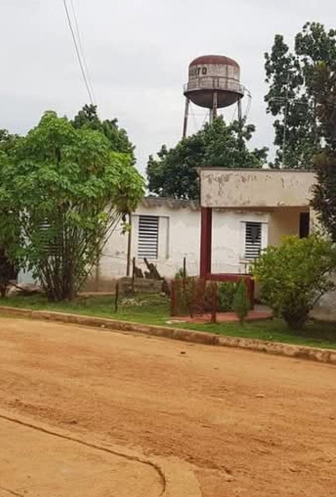 Casa blanca y torre de agua en un entorno rural.