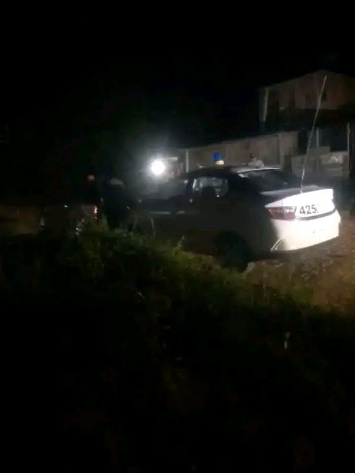 Coche de policía blanco estacionado de noche en zona oscura.