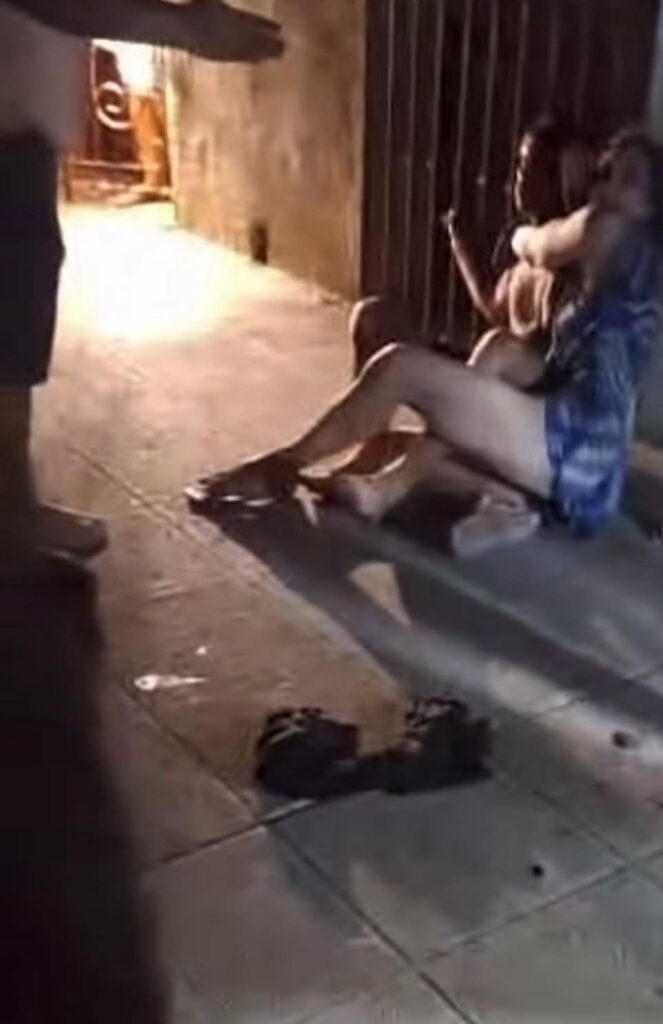 Persona sujetando a otra en una acera de noche.