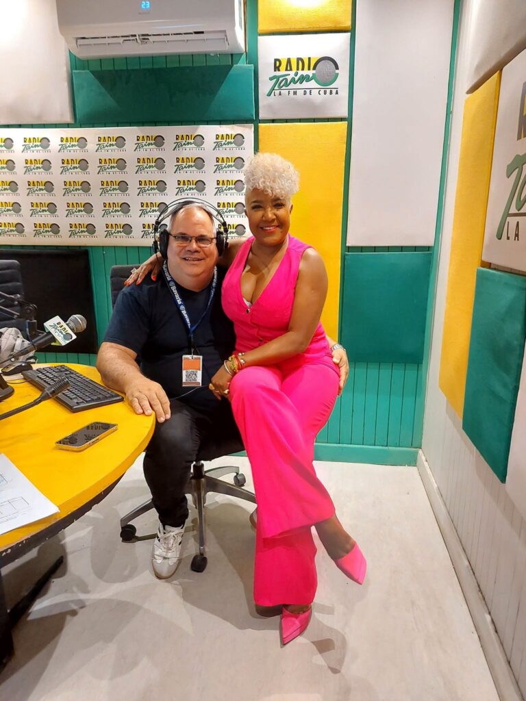 Dos personas posando sonrientes en un estudio de radio.