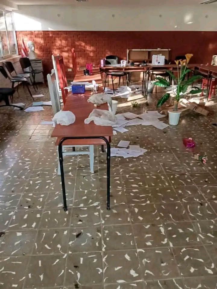 Aula desordenada con multitud de papeles esparcidos por el suelo.