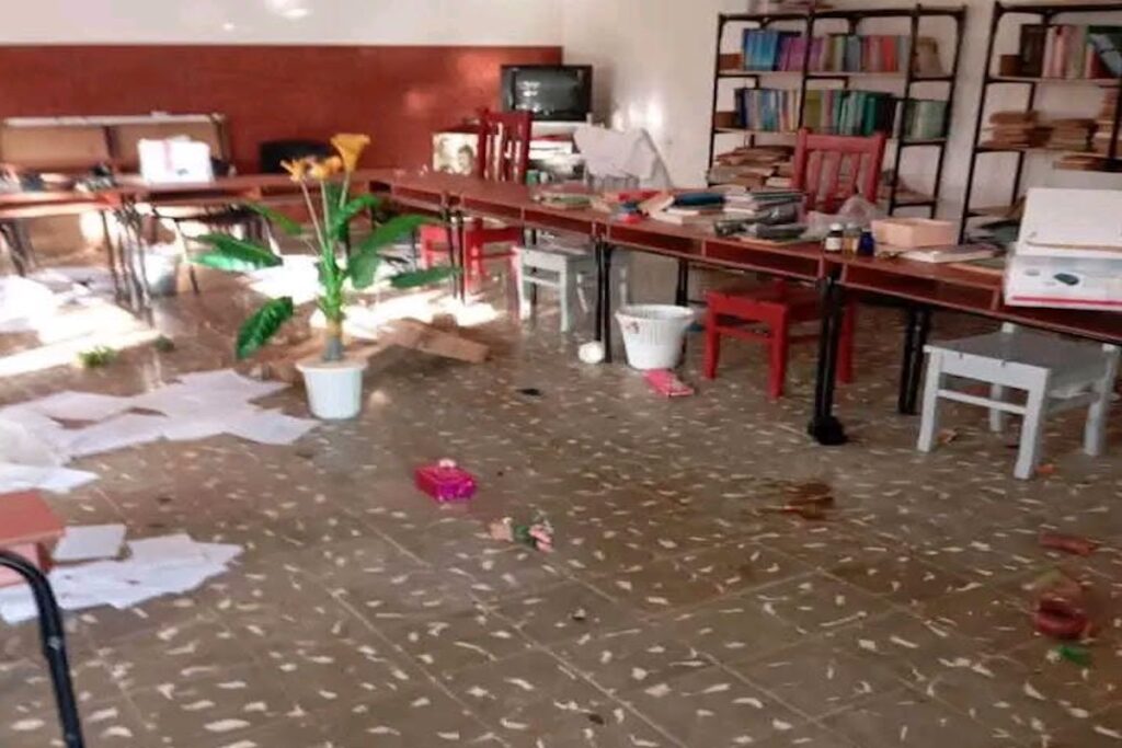 Sala de estudio vandalizada con papeles y objetos esparcidos.