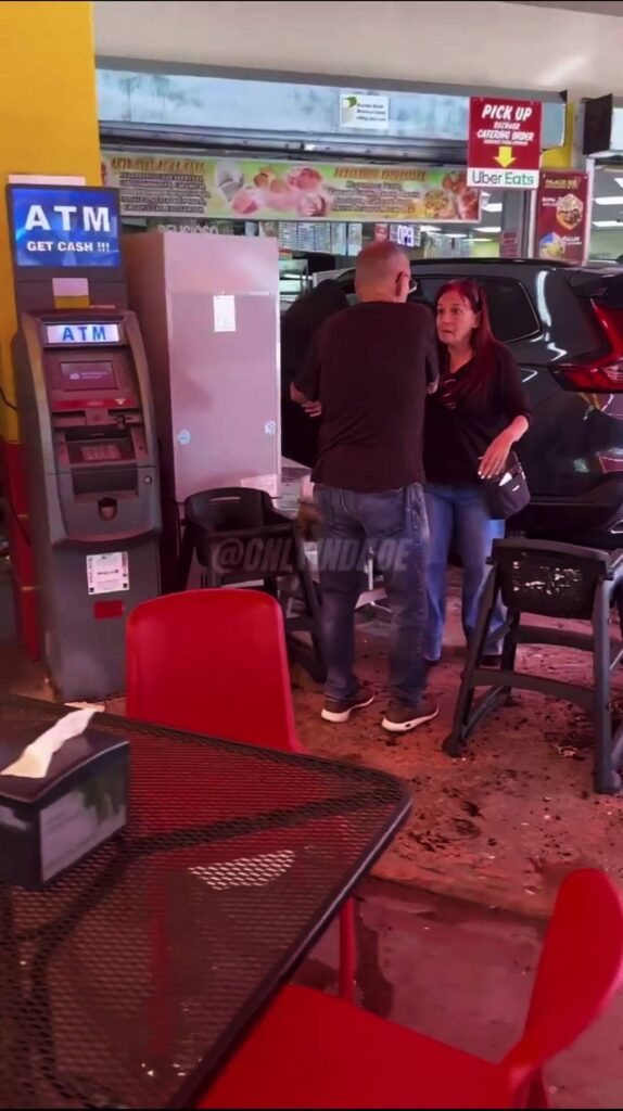 Coche empotrado en un restaurante con escombros y personas.