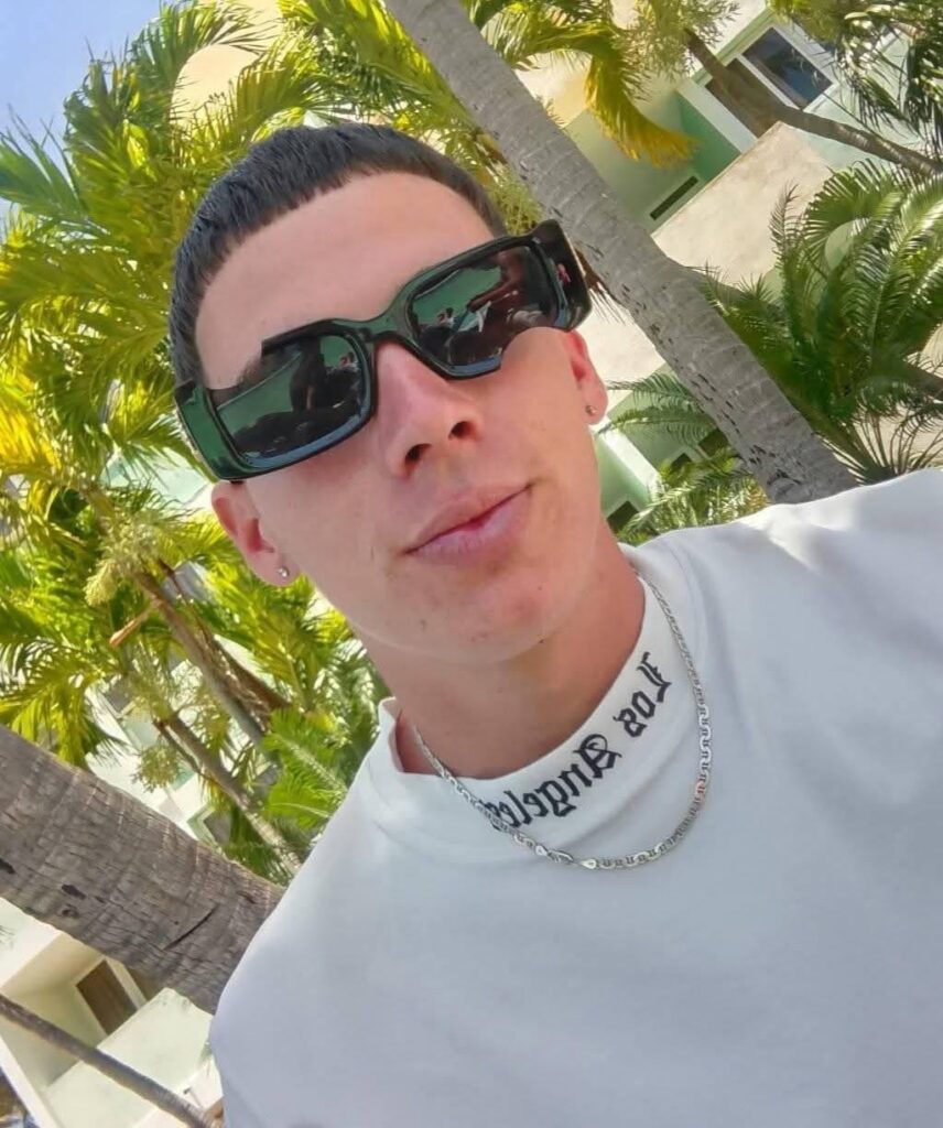 Hombre joven con gafas de sol rectangulares y camiseta blanca.