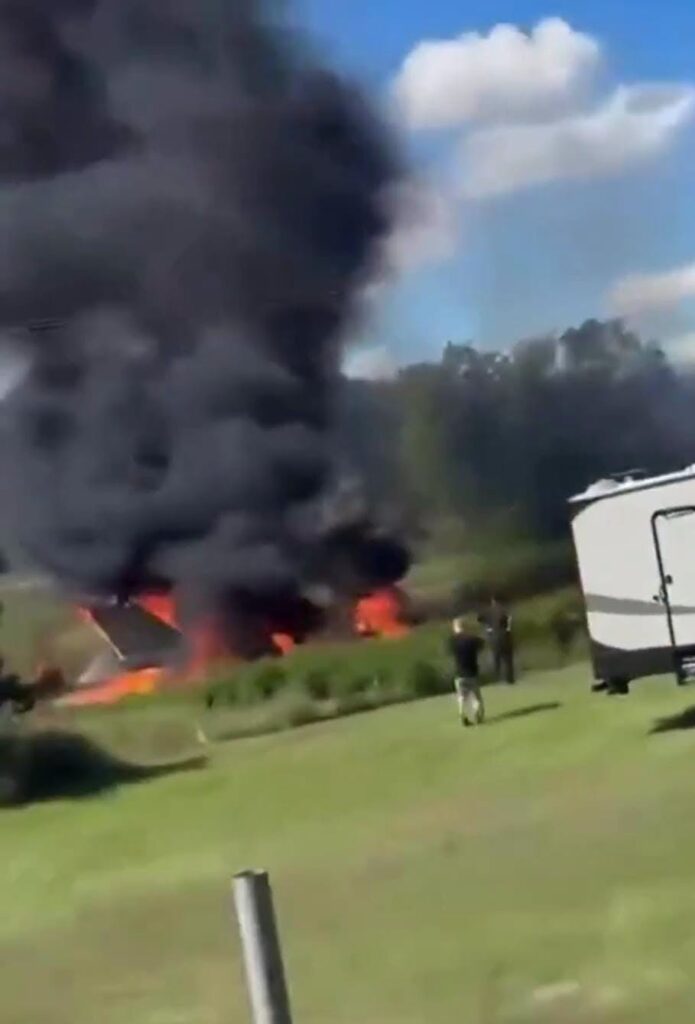 Gran columna de humo negro y fuego en un campo.