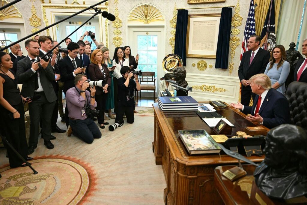 Donald Trump en el Despacho Oval rodeado de periodistas.