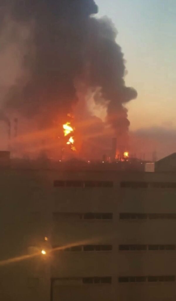 Incendio masivo en una zona industrial al atardecer.
