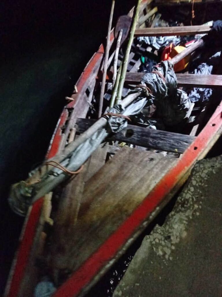 Barca de madera cargada con remos y bultos por la noche.