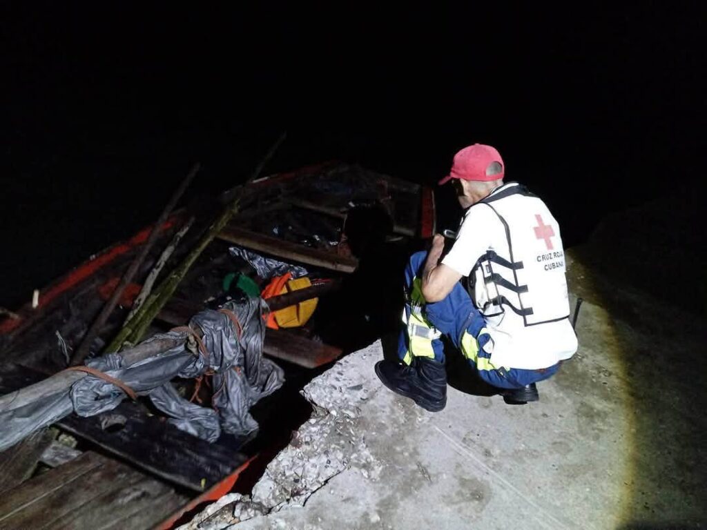 Voluntario de Cruz Roja Cubana inspeccionando una embarcación de noche.