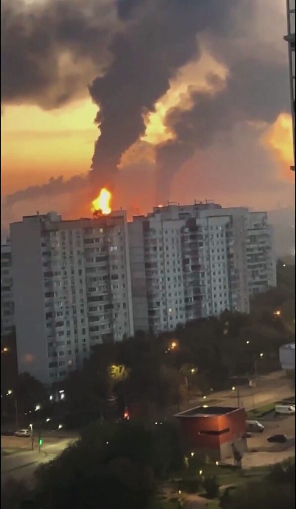 Gran incendio con humo negro detrás de edificios de apartamentos.