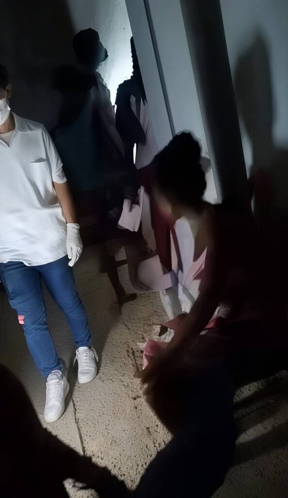 Persona con guantes y mascarilla en un ambiente oscuro.