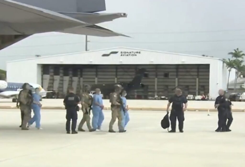 Escolta de seguridad a personas en uniformes azules en aeropuerto.