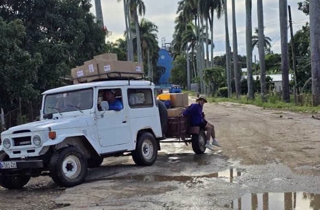 Todoterreno blanco transportando cajas por un camino de tierra.