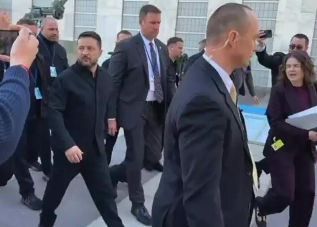 Volodymyr Zelensky caminando rodeado de personal de seguridad y ayudantes.