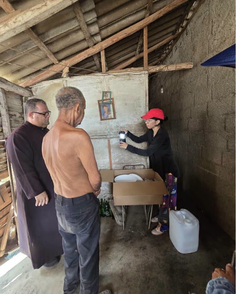 Voluntaria entregando suministros a un hombre y un clérigo.